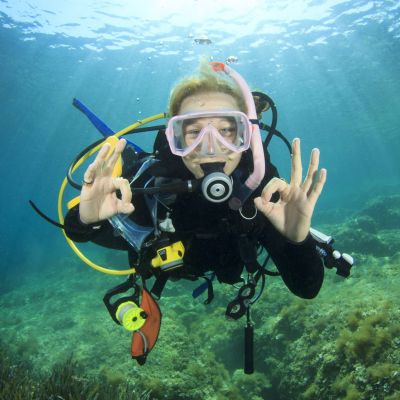 Young woman scuba diving signals okay